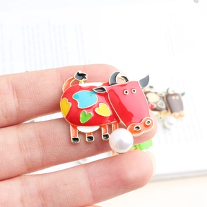 Detail of red enamel cow brooch with colorful heart patterns and a white pearl accent