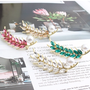 Macro detail of wheat ear brooches with colorful marquise crystals and white faux pearls