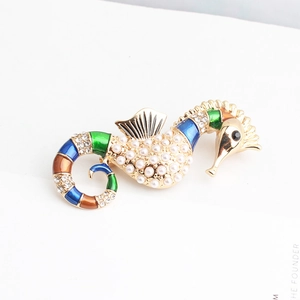 Détail d'une broche hippocampe avec perles blanches, cristaux et émail coloré