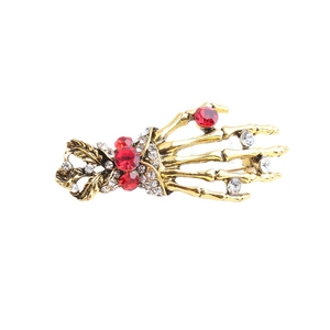 Gothic skull hand brooch in vintage gold with red rubies and white crystal accents