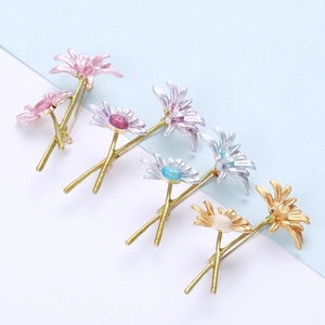 Detail view of five enamel daisy brooches in pink, purple, blue, silver, and orange