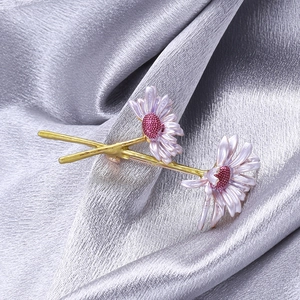 Macro detail of enamel daisy brooch with purple petals, red stamens, and golden stems