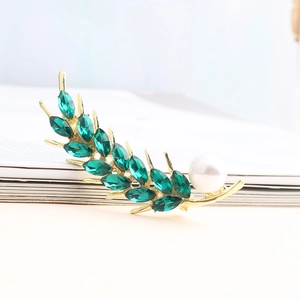 Elegant gold wheat brooch with green crystals and white pearl accent on book edge