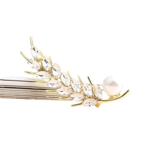 Elegant gold wheat ear brooch with sparkling crystals and a white pearl on white surface