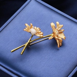 Detailed macro shot of golden daisy brooch with matte petals on dark blue box