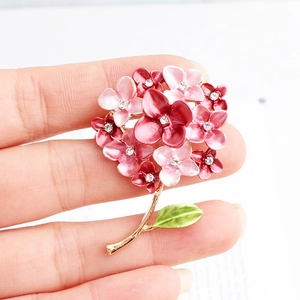 Close-up of pink flower brooch with enamel petals and central rhinestone accents