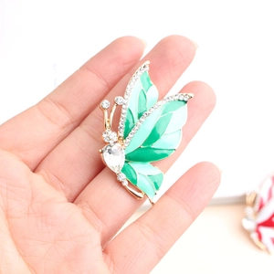 Detail view of a vintage butterfly brooch with green enamel and sparkling rhinestones