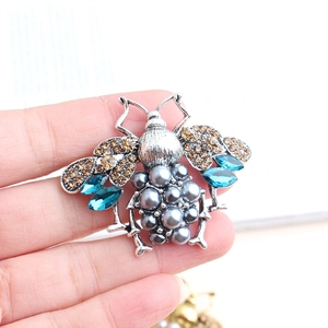Detail of bee brooch with vintage silver finish, grey pearls and blue crystals