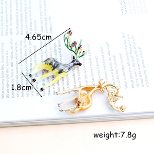 Cute enamel elk reindeer brooches set with crystal rhinestones on a vintage book backdrop