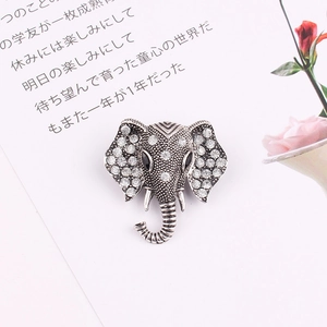 Detailed view of silver elephant brooch with crystals on a textured paper background