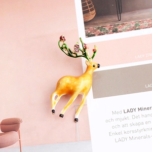 Detail shot of a cartoon reindeer brooch with yellow enamel and green antlers on a magazine