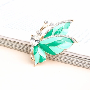 Elegant gold-plated butterfly brooch with green enamel wings and sparkling rhinestones