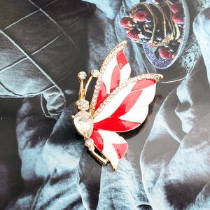 Elegant gold butterfly brooch with red and white enamel wings and sparkling crystals