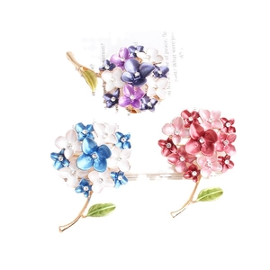 Elegant floral enamel brooches set with rhinestones and gold-tone finish on white backdrop