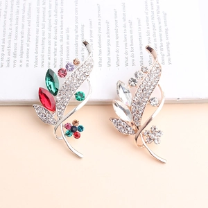Detail of colorful crystal and clear rhinestone leaf brooches on a magazine background