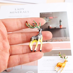 Close-up of a colorful enamel reindeer brooch with green antlers and sparkling crystals