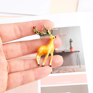 Detailed close-up of a colorful enamel reindeer brooch held by hand for size reference