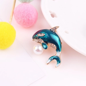 Close-up of blue enamel dolphin brooch with sparkling crystals and a large white pearl