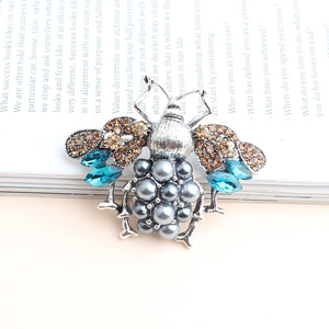 Vintage bee brooch featuring grey pearls and colorful rhinestones on a silver metal base