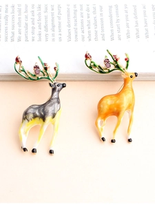 Detail of two cute elk brooches with colorful enamel finish on an open book
