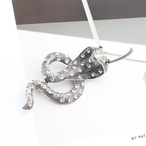 Détail macro d'une broche serpent argentée sertie de strass en cristal et d'yeux en gemmes noires
