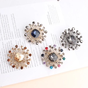 Close-up of four floral starburst brooches with faceted crystals and golden alloy base