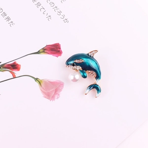 Green enamel dolphin brooch pin with crystal rhinestones and pearl on white background