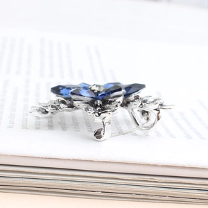 Vintage silver flower brooch with deep blue crystals and gray rhinestone on a book