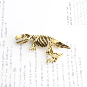 Détail d'une broche squelette de dinosaure en alliage doré vintage sur une page
