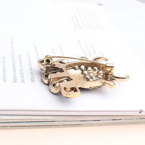 Achterkant van vintage gouden dierenbroche met veiligheidsspeld en getextureerde legering