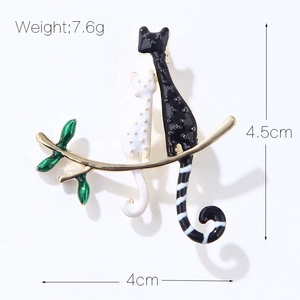 Broche créative en émail avec deux chats s'enlaçant sur une branche aux feuilles vertes