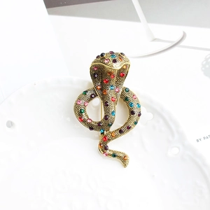 Détail de la broche cobra avec strass colorés sur une finition en métal doré antique