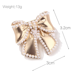 Chic bow-shaped enamel brooch with golden metal base and elegant white pearls decoration