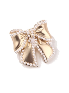 Detailed close-up of golden bow brooch with white faux pearls and enamel texture