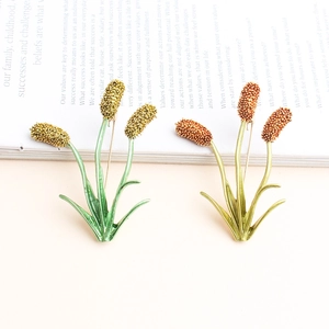 Detailed macro view of plant wheat enamel brooches in green and golden finish