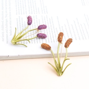 Detailed macro view of purple and orange enamel flower brooches on a magazine page