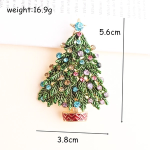 Makroaufnahme einer grünen Emaille-Weihnachtsbaum-Brosche mit bunten Steinen und Vergoldung