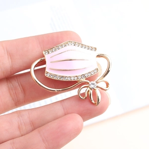 Detailed view of pink enamel medical mask brooch with rhinestones and golden bow