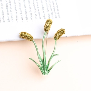 Golden wheat ears brooch with green leaves on a vintage book background