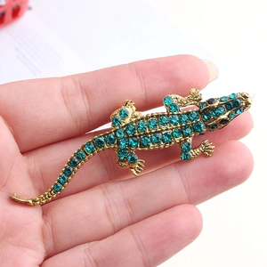 Vue détaillée d'une broche crocodile avec strass verts et finition métal doré
