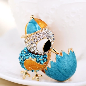 Macro shot of chick hatching from egg brooch with blue rhinestones and enamel details