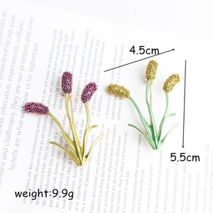 Elegant wheat flower enamel brooches in purple and yellow on a magazine backdrop