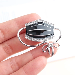 Detail of silver alloy bow and black enamel mask brooch set with white rhinestones