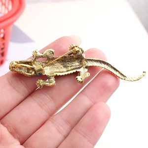 Détail du dos de la broche crocodile dorée avec épingle de sûreté et petite pierre verte