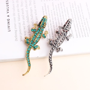 Broches crocodiles étincelantes en cristal doré et argenté sur un livre ancien