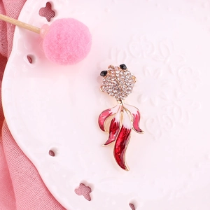 Primer plano de un broche de pez dorado con pedrería brillante y esmalte rosa suave