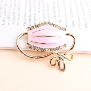Creative pink enamel face mask brooch with gold bow and sparkling rhinestones