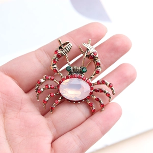 Détail de la broche crabe dorée avec cristaux rouges et pierre d'opale rose
