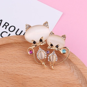 Détail de broches chat avec pierres d'opale et strass colorés sur plateau bois