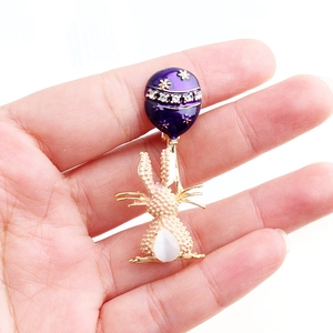 Dettaglio di una spilla a coniglio con palloncino in smalto viola e opale bianco